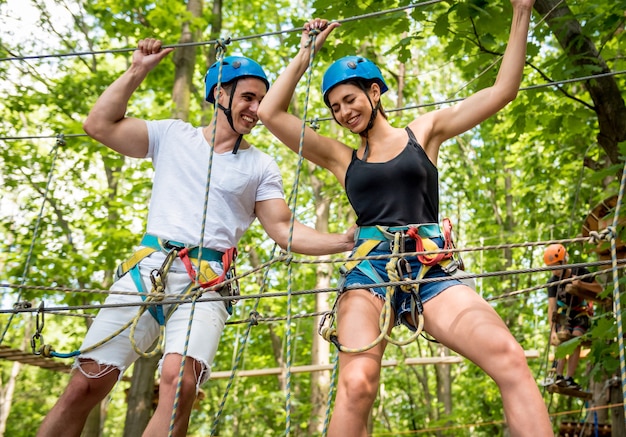 Jovem casal se divertindo no parque de corda aventura.