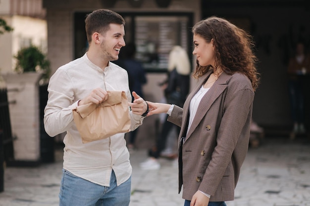 Jovem casal segura comida para viagem nas mãos e sorri para a câmera Espaço para texto