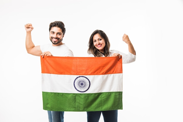 Jovem casal segurando bandeira indiana no dia da independência ou da república, em pé isolado sobre fundo branco. foco seletivo