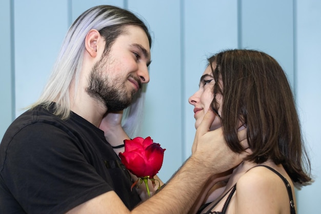 Jovem casal segurando uma rosa olhando um para o outro com ternura