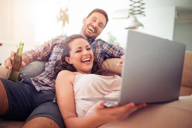 Foto jovem casal sentado na sala de estar e usando laptop