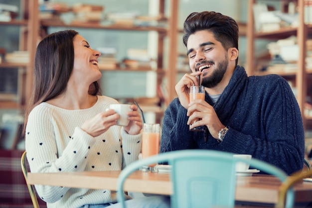 Jovem casal sentado no café e rindo