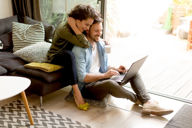 Jovem casal sentado no chão e usando o notebook.