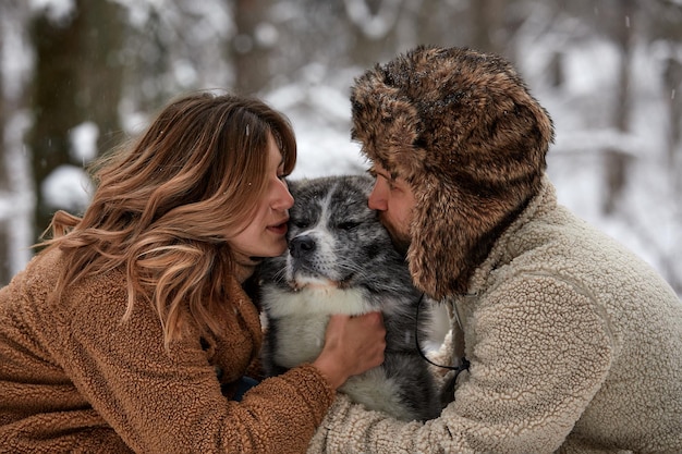 Jovem casal sorrindo e se divertindo em winter park com seu cachorro husky