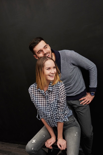 Jovem casal sorrindo juntos contra de fundo preto. foto de estúdio