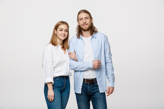 jovem casal sorrindo para a câmera, mantendo o braço para armar.