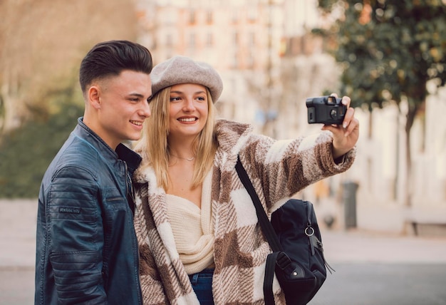 Foto jovem casal tira um autorretrato com uma câmera velha na rua
