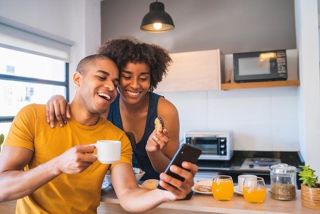 Jovem casal tomando selfie enquanto tomando café da manhã em casa.