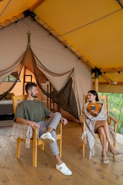 Jovem casal tranquilo sentado em poltronas de madeira