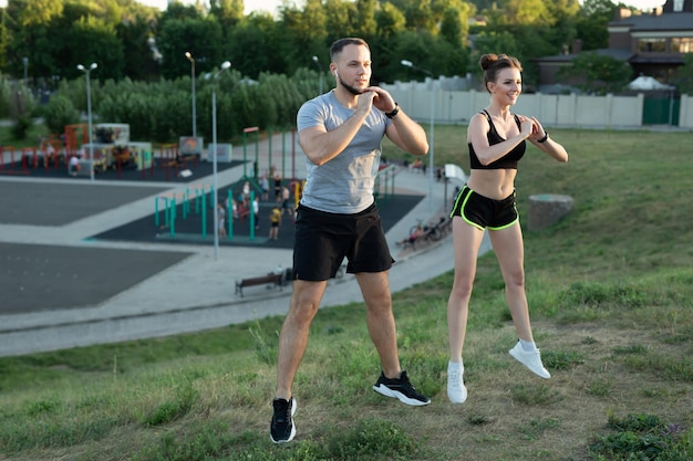 Jovem casal treina ao ar livre em um parque no verão ao pôr do sol