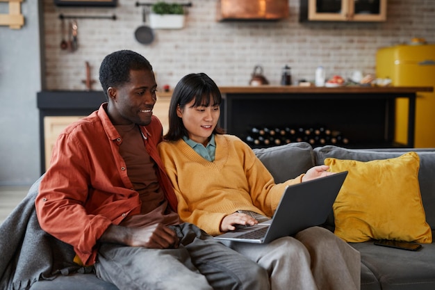 Jovem casal usando laptop no sofá