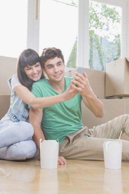 Jovem casal usando telefone celular em sua nova casa