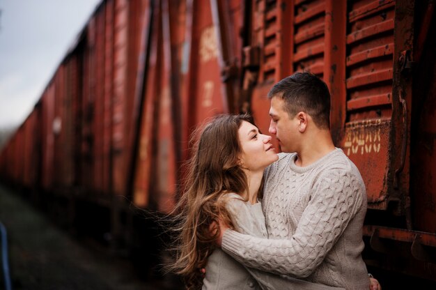 Jovem casal vestindo blusas quentes amarradas, abraçando no amor nas estações ferroviárias