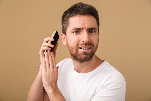 Jovem casual confuso segurando o celular isolado