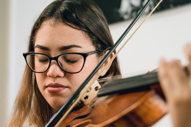 Jovem caucasiana com olhos fechados tocando e sentindo a música do violino