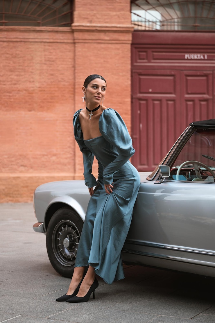 Foto jovem caucasiana usando um vestido descansando no capô do carro na frente da praça de touros
