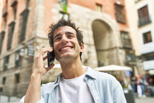 Jovem caucasiano conversando alegremente em seu telefone desfrutando de um passeio ao ar livre