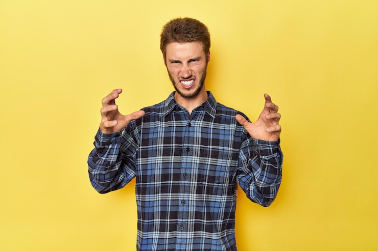 Foto jovem caucasiano em um fundo de estúdio amarelo gritando de raiva