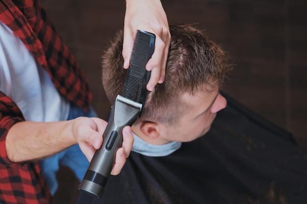 Jovem caucasiano na barbearia Barber está cortando o cabelo no estilo hipster