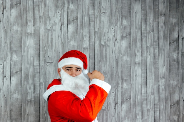 Jovem caucasiano vestido de Papai Noel com o punho no ar. Copie o espaço no topo