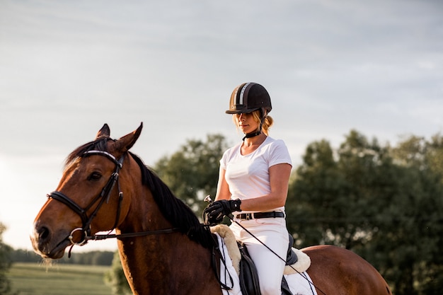 Jovem cavalga a cavalo no fundo da natureza. Esportes e saúde. Recreação ativa.