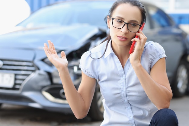 Jovem chateada falando ao telefone no contexto das consequências do acidente de carro quebrado