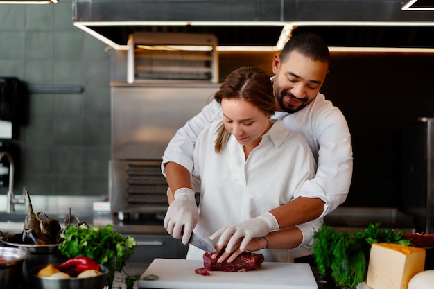 Foto jovem chef africano está cozinhando junto com a namorada caucasiana na cozinha