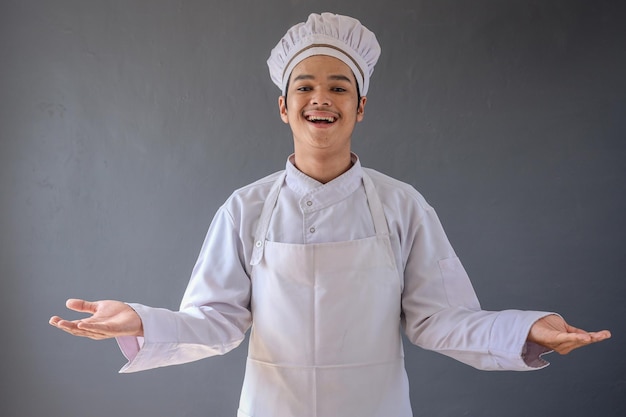 Jovem chef asiático sorridente e feliz em avental branco com gesto de mão