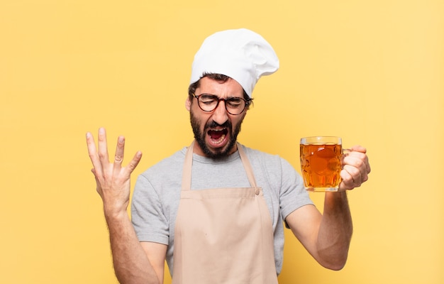 Jovem chef barbudo com expressão de raiva e segurando uma cerveja