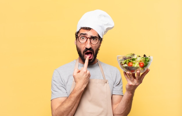 Jovem chef barbudo com expressão triste e segurando uma salada