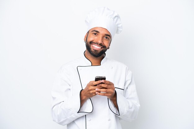 Jovem chef brasileiro isolado em fundo branco enviando uma mensagem com o celular