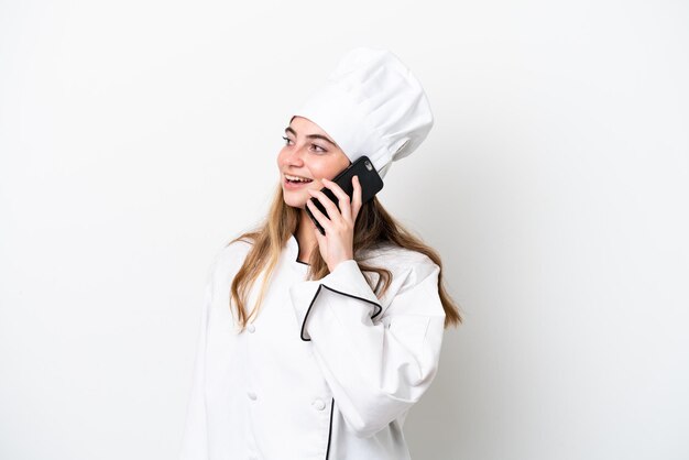 Foto jovem chef caucasiana isolada em fundo branco mantendo uma conversa com o telefone celular