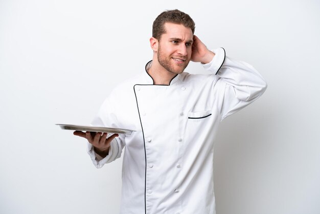 Jovem chef caucasiano com bandeja isolada no fundo branco com dúvidas