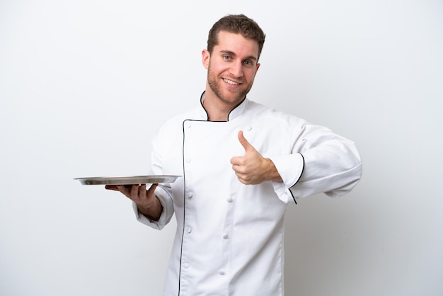 Jovem chef caucasiano com bandeja isolada no fundo branco, dando um polegar para cima gesto