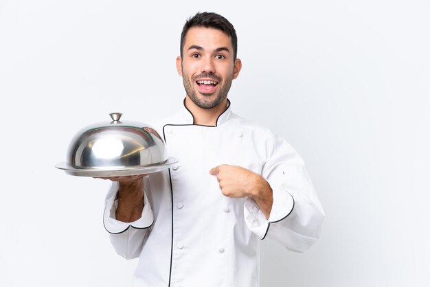 Jovem chef com bandeja isolada no fundo branco com expressão facial de surpresa