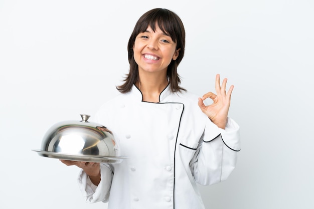 Jovem chef com bandeja isolada no fundo branco, mostrando sinal de ok com os dedos