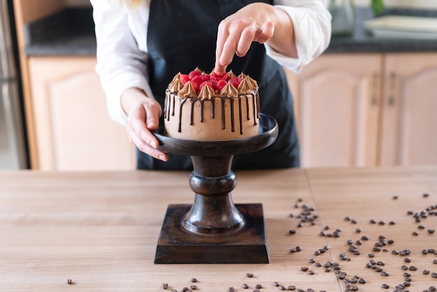 Jovem chef confeiteiro cozinhando um delicioso bolo caseiro de chocolate com frutas na cozinha