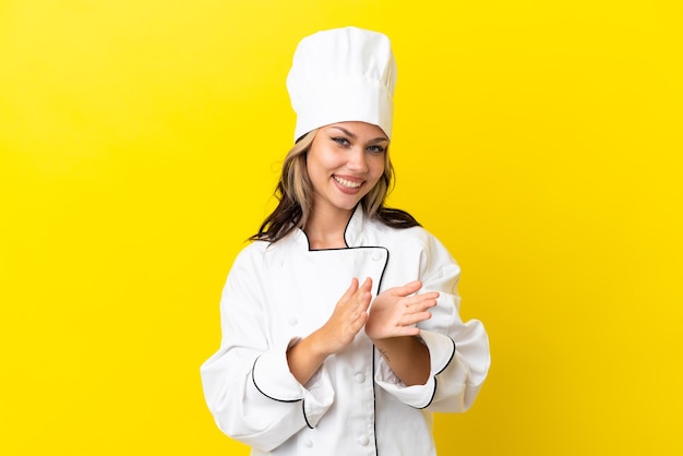 Jovem chef russa isolada em fundo amarelo aplaudindo após apresentação em uma conferência