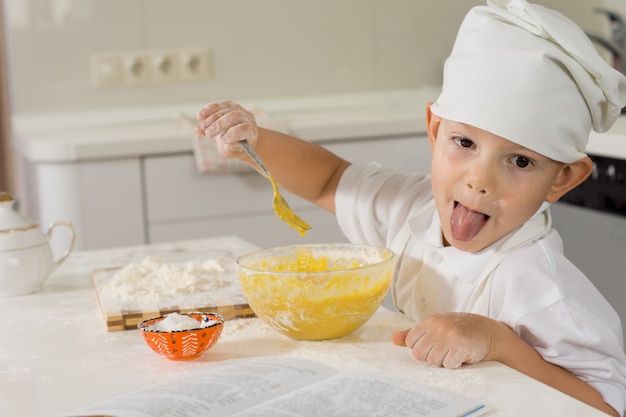 Jovem chef tolo mostrando a língua enquanto mistura sua massa