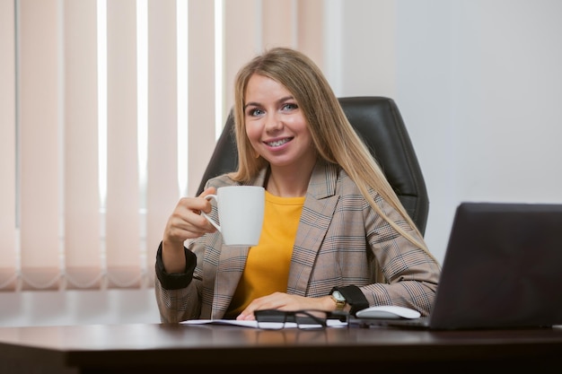 Jovem chefe alegre está segurando uma xícara de café em seu escritório coffee break