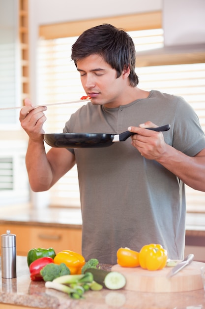 Jovem cheirando comida na cozinha