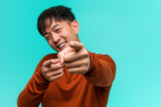 Jovem chinês alegre e sorridente apontando para a frente