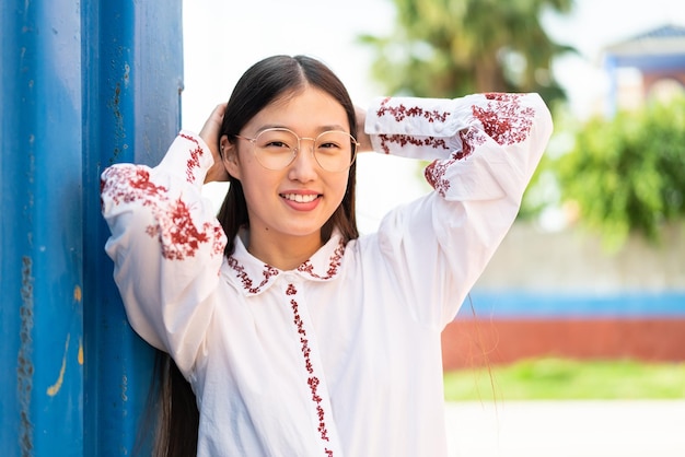 Jovem chinesa ao ar livre com expressão feliz