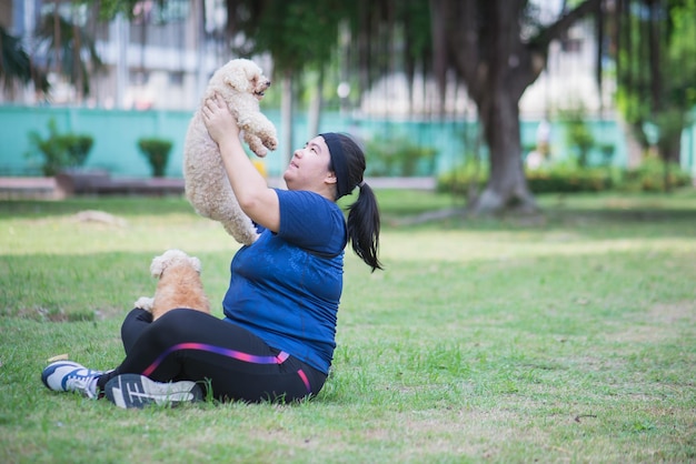 Jovem chinesa ao ar livre na paisagem do parque público e segurando cachorro