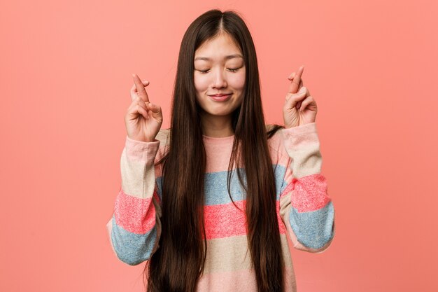 Jovem chinesa descolada cruzando os dedos por ter sorte