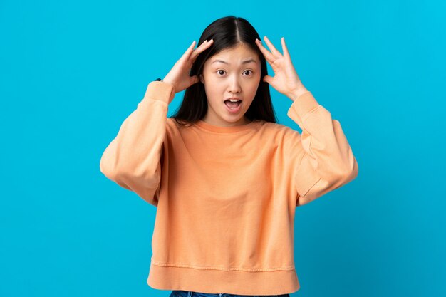Jovem chinesa em azul isolado com expressão de surpresa