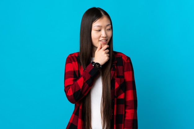 Jovem chinesa em azul isolado, olhando para o lado e sorrindo