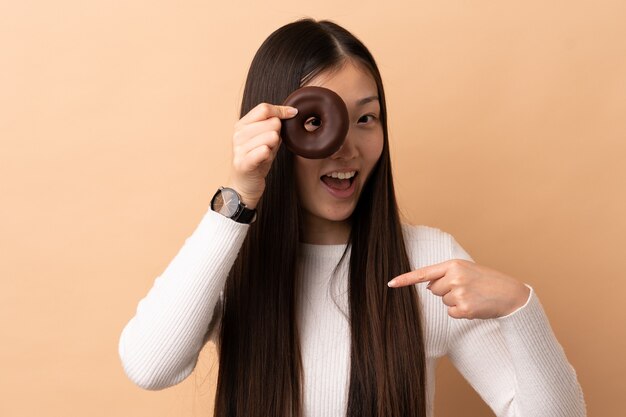 Jovem chinesa em um fundo isolado segurando um donut e feliz