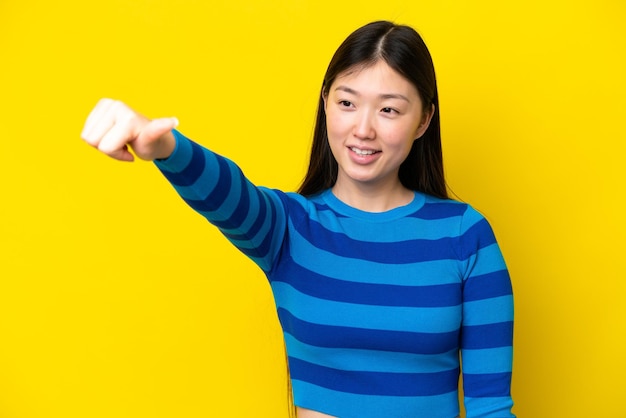 Jovem chinesa isolada em fundo amarelo dando um polegar para cima gesto