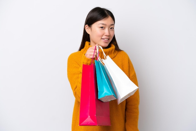 Jovem chinesa isolada em fundo branco segurando sacolas de compras e sorrindo